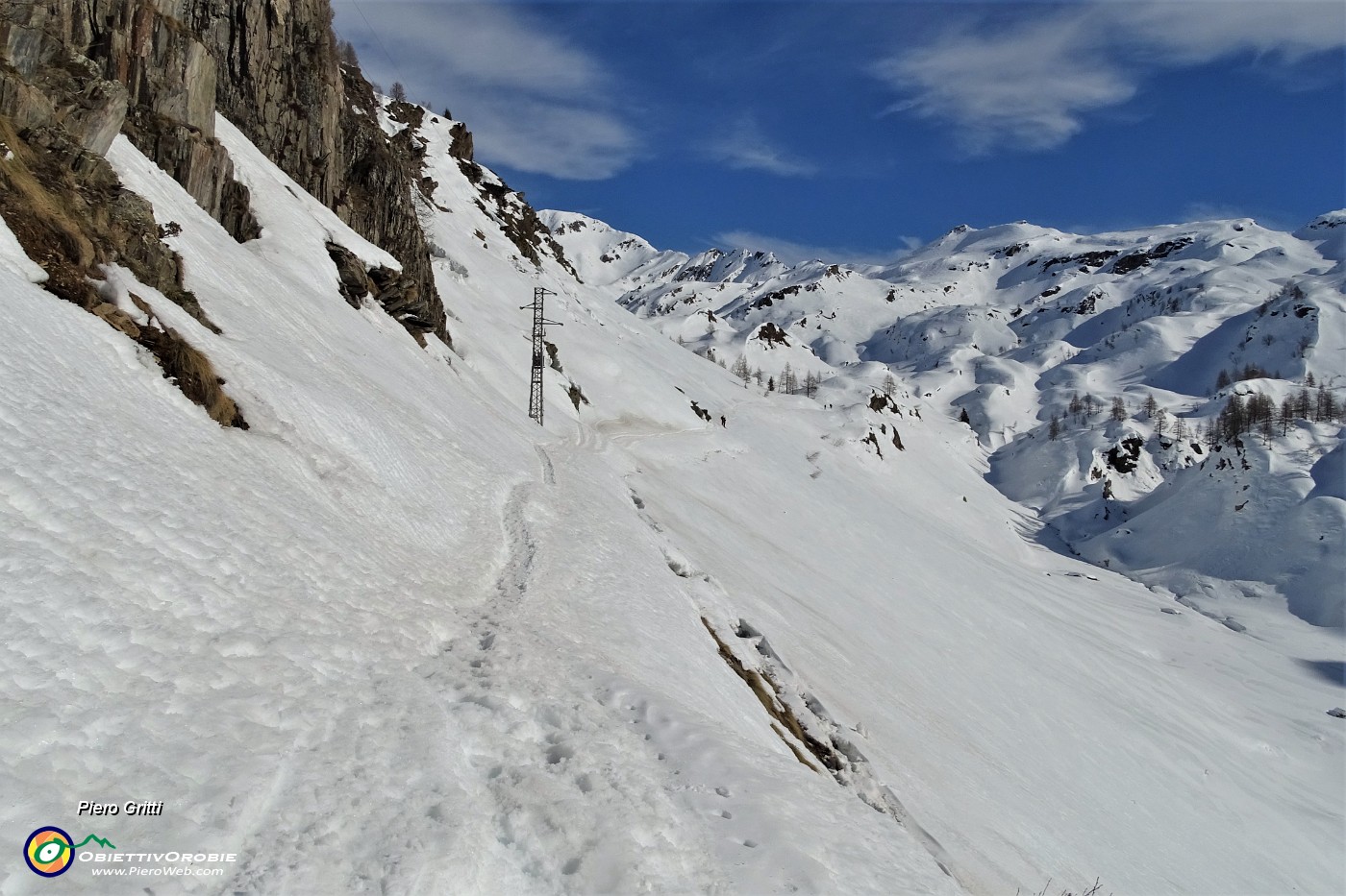 55 In cammino sulla traccia scavata nella neve sul ripido pendio dell'invaso del lago ...senz'acqua, bianco di neve con vista sul Madonnino.JPG